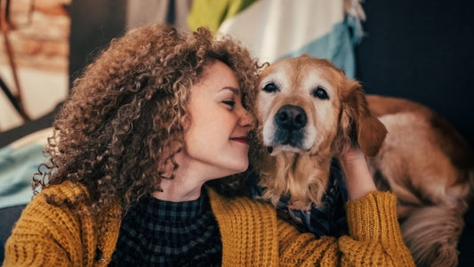 Woman cuddling her golden retriever at home on couch